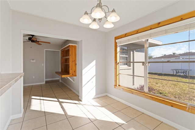 unfurnished dining area with plenty of natural light, light tile patterned floors, and ceiling fan with notable chandelier