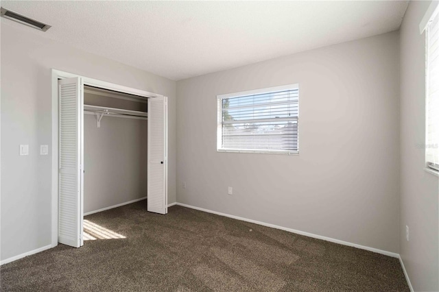 unfurnished bedroom featuring a closet and dark carpet