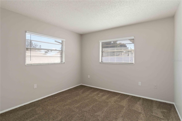 unfurnished room featuring a textured ceiling and dark colored carpet