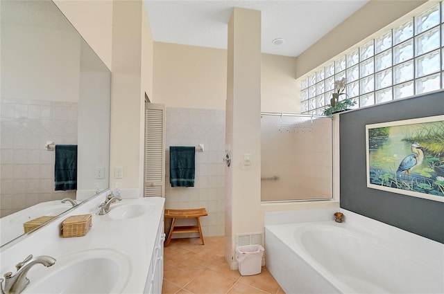 bathroom with vanity, a bath, tile patterned flooring, a textured ceiling, and tile walls