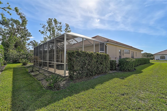 view of side of home with glass enclosure and a yard