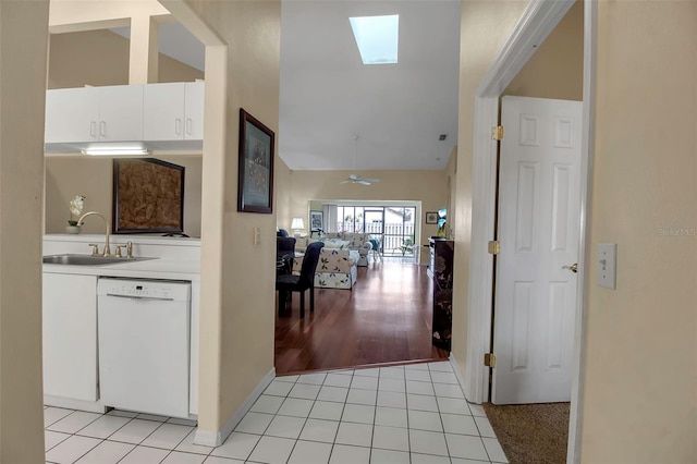 corridor featuring lofted ceiling with skylight, sink, and light tile patterned floors