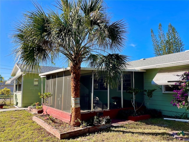 view of side of property with a lawn and a sunroom