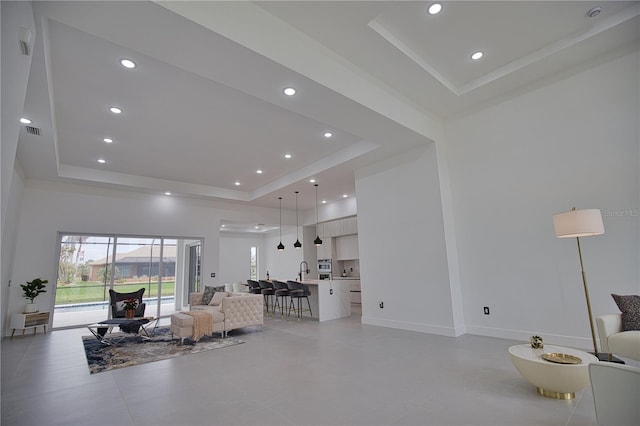 living room with a raised ceiling and sink