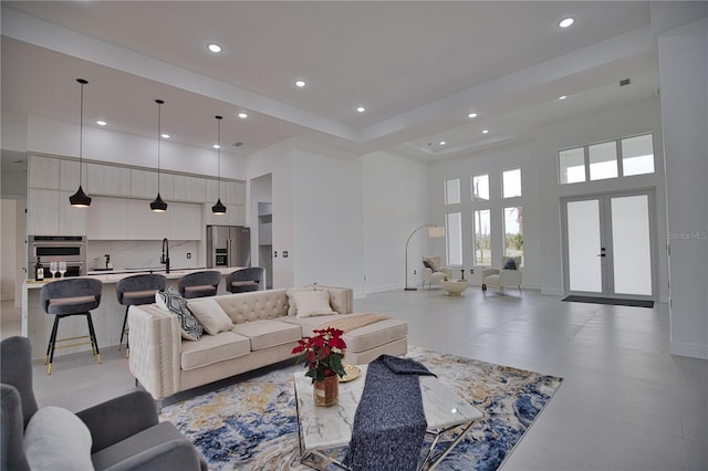 living room featuring french doors, a towering ceiling, and sink