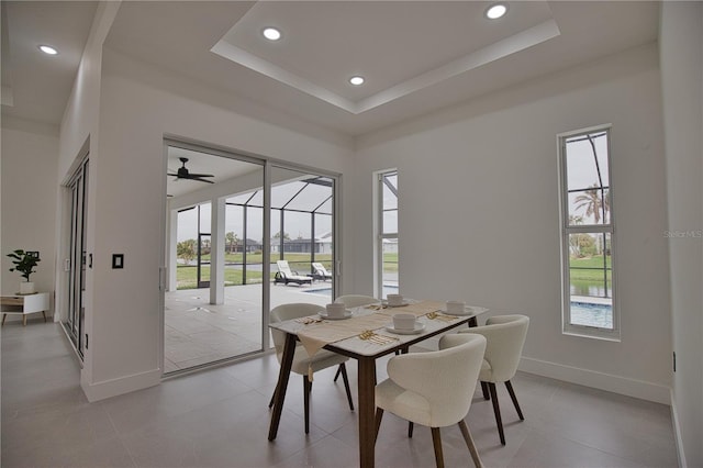 dining room with ceiling fan, a healthy amount of sunlight, and a tray ceiling