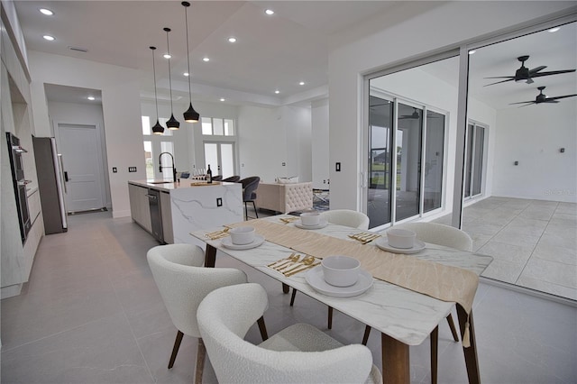 tiled dining space featuring ceiling fan, a healthy amount of sunlight, and sink