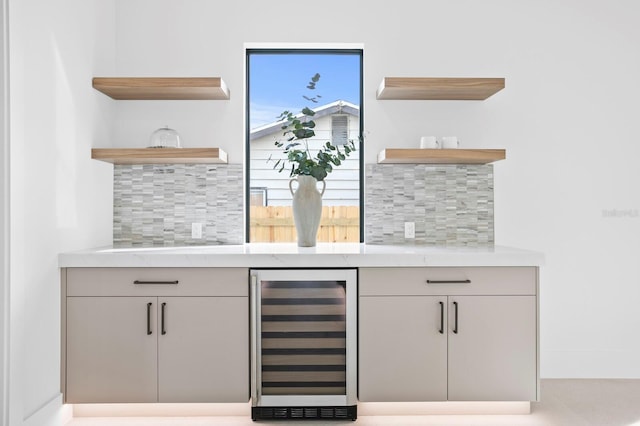 bar featuring light stone counters, backsplash, and beverage cooler