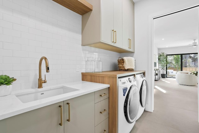 laundry area with cabinets, washing machine and clothes dryer, ceiling fan, and sink