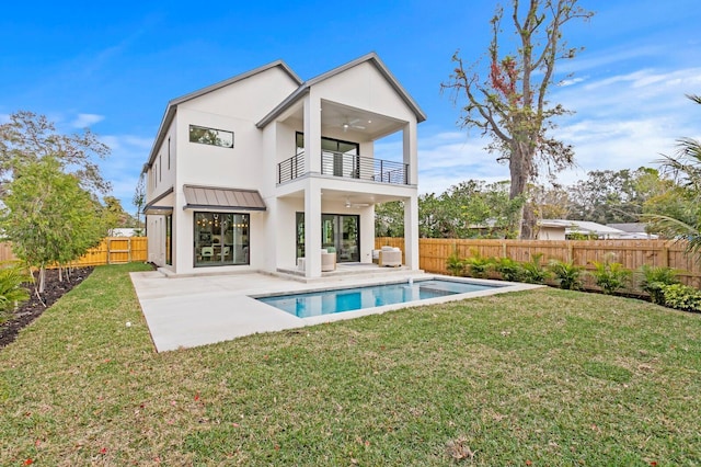 rear view of house featuring a patio, a balcony, a lawn, ceiling fan, and a fenced in pool