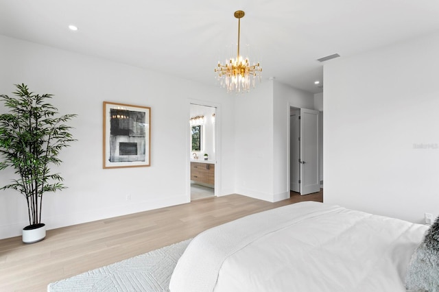 bedroom featuring hardwood / wood-style flooring, connected bathroom, and a notable chandelier