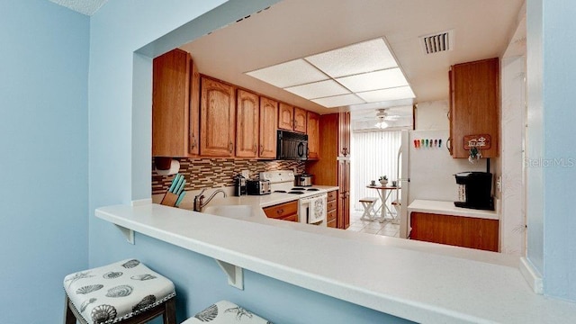 kitchen with kitchen peninsula, decorative backsplash, ceiling fan, sink, and white electric stove