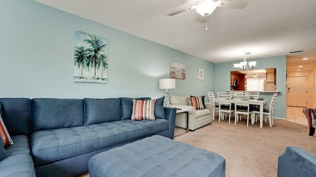 living room with ceiling fan with notable chandelier, a textured ceiling, and light colored carpet