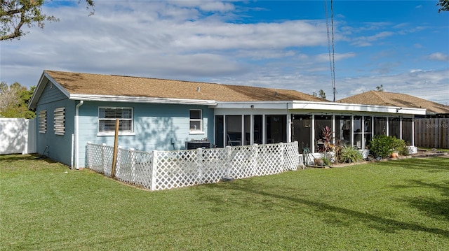 rear view of house featuring a sunroom and a yard