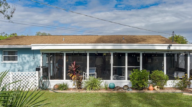 rear view of house with a lawn and a sunroom