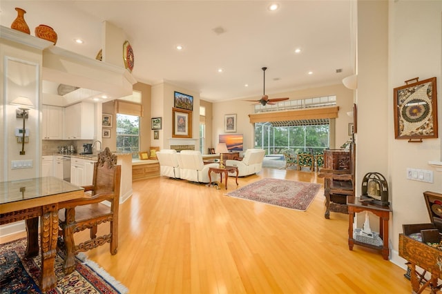 living room featuring ceiling fan, crown molding, and light hardwood / wood-style flooring