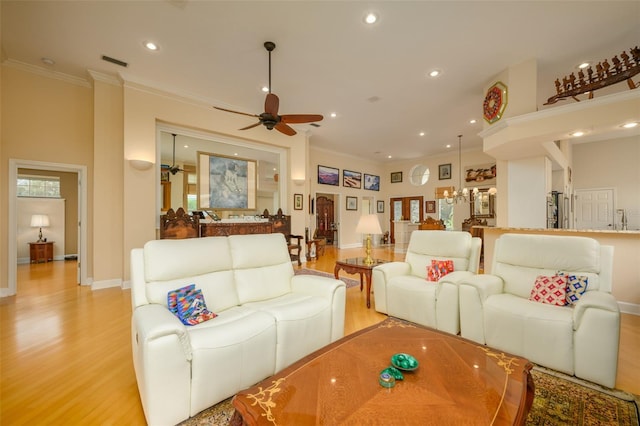 living room with ceiling fan with notable chandelier, light wood-type flooring, and crown molding