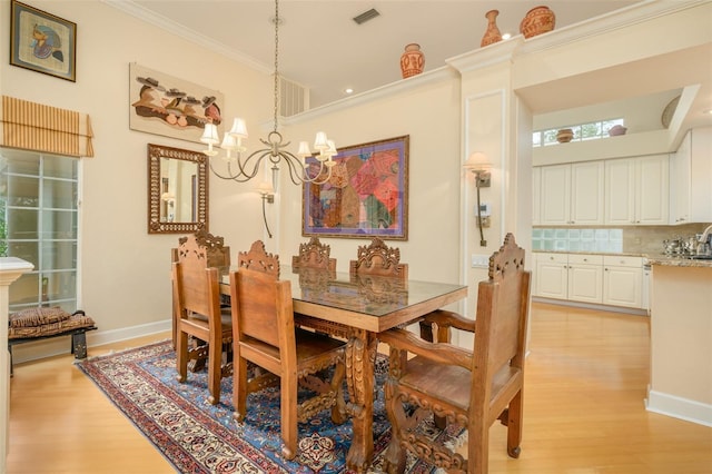 dining area featuring ornamental molding, light hardwood / wood-style floors, a notable chandelier, and sink