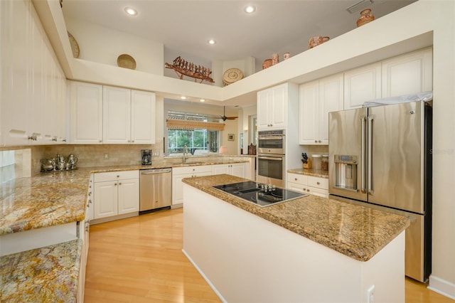 kitchen featuring appliances with stainless steel finishes, sink, light hardwood / wood-style flooring, a center island, and white cabinetry