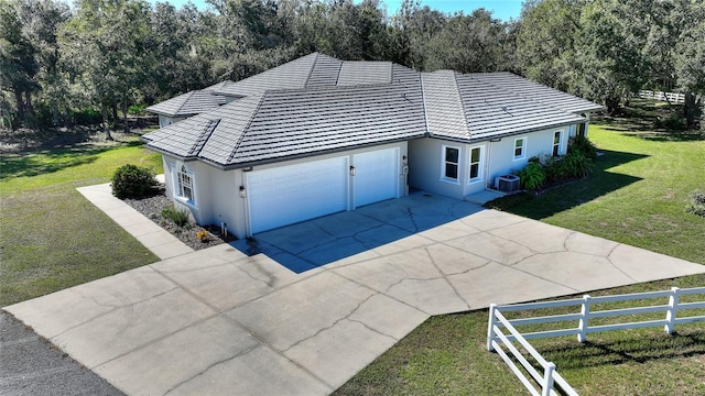 view of property exterior with a garage, central AC, and a lawn