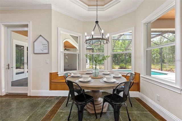 dining space with a raised ceiling, crown molding, and a chandelier