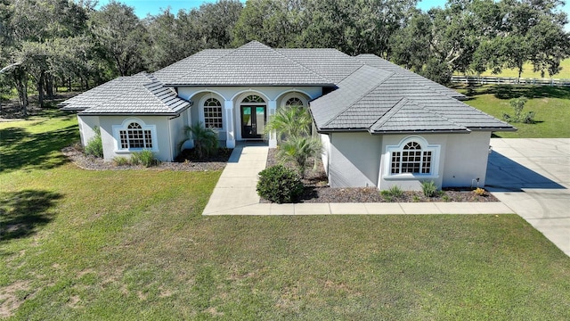 mediterranean / spanish-style home featuring a tile roof, a front lawn, and stucco siding