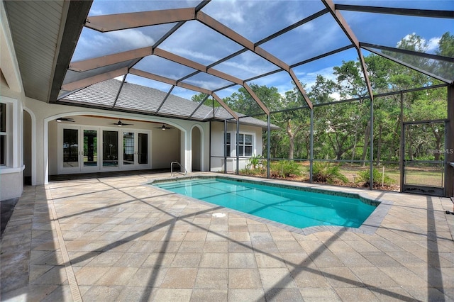 outdoor pool featuring glass enclosure, a ceiling fan, a patio, and french doors