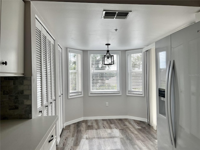 unfurnished dining area with an inviting chandelier and light hardwood / wood-style flooring