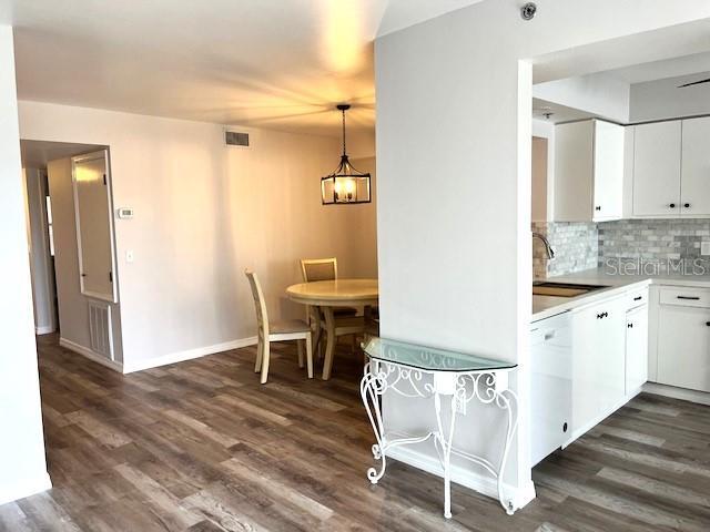 kitchen featuring white cabinetry, sink, dark hardwood / wood-style flooring, backsplash, and decorative light fixtures