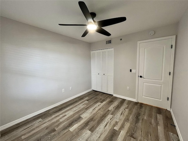 unfurnished bedroom featuring a closet, ceiling fan, and dark hardwood / wood-style flooring