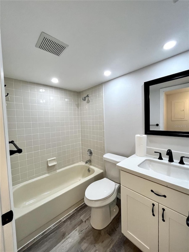 full bathroom featuring vanity, wood-type flooring, tiled shower / bath combo, and toilet