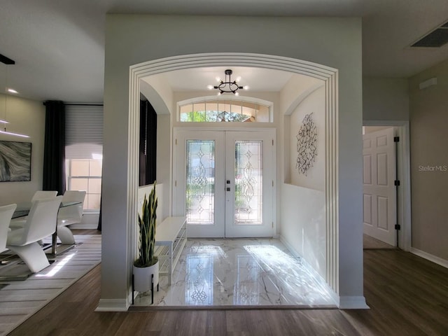 entrance foyer featuring french doors, an inviting chandelier, and hardwood / wood-style flooring