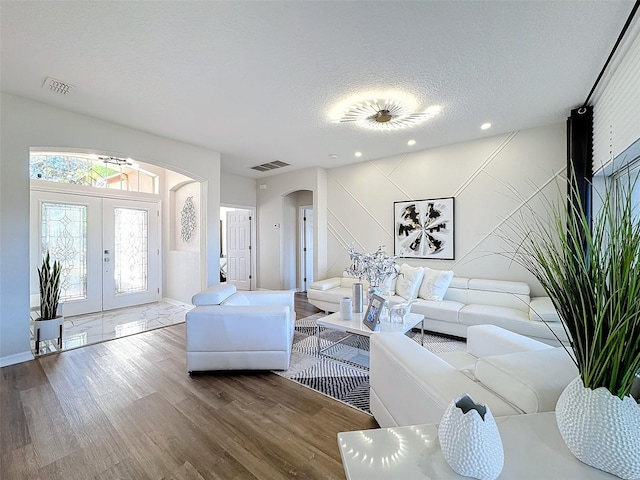 living room featuring wood-type flooring, a wealth of natural light, french doors, and a textured ceiling