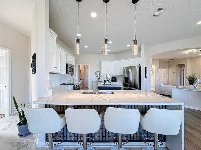 kitchen featuring appliances with stainless steel finishes, white cabinets, a kitchen bar, and kitchen peninsula