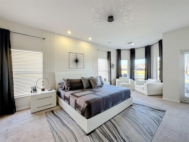 bedroom featuring multiple windows, light carpet, and a textured ceiling