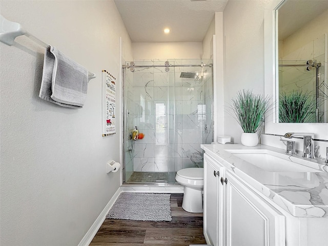 bathroom with hardwood / wood-style flooring, vanity, toilet, and a shower with door