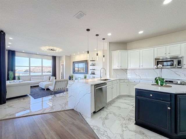 kitchen featuring sink, appliances with stainless steel finishes, white cabinetry, decorative backsplash, and decorative light fixtures