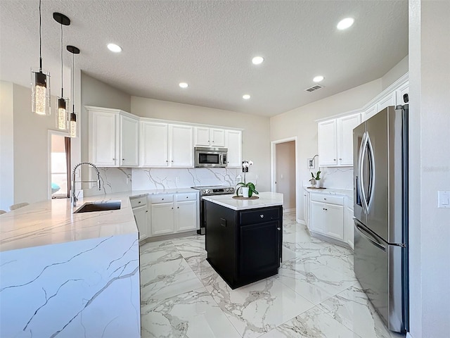 kitchen featuring appliances with stainless steel finishes, sink, white cabinets, a center island, and a textured ceiling