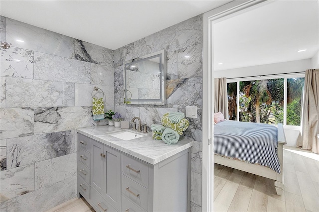 bathroom with tile walls, vanity, and hardwood / wood-style floors