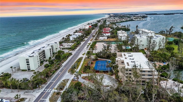 aerial view at dusk with a water view and a view of the beach