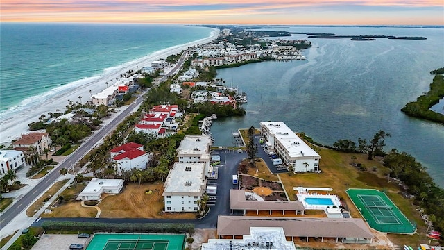 aerial view at dusk featuring a view of the beach and a water view