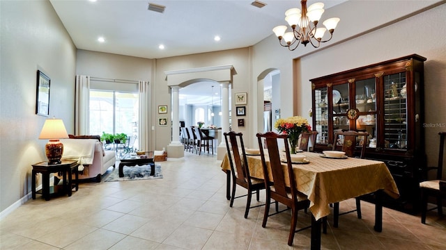 tiled dining room featuring decorative columns and a notable chandelier