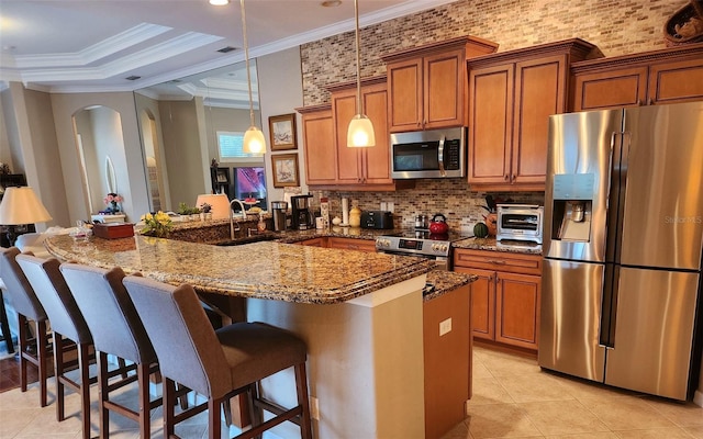 kitchen with a breakfast bar area, crown molding, hanging light fixtures, and stainless steel appliances