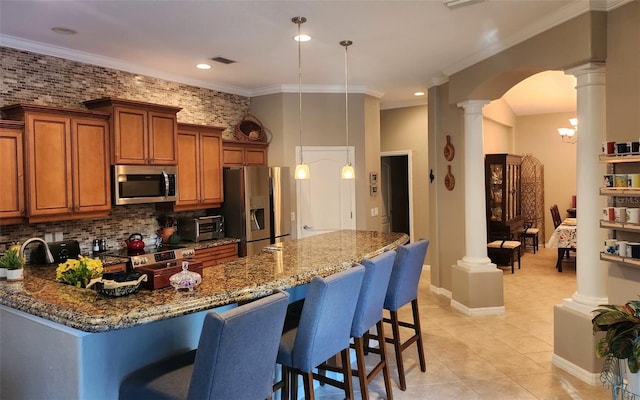 kitchen with stainless steel appliances, dark stone countertops, decorative light fixtures, a breakfast bar area, and ornamental molding