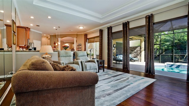 living room featuring dark hardwood / wood-style flooring, a raised ceiling, and crown molding