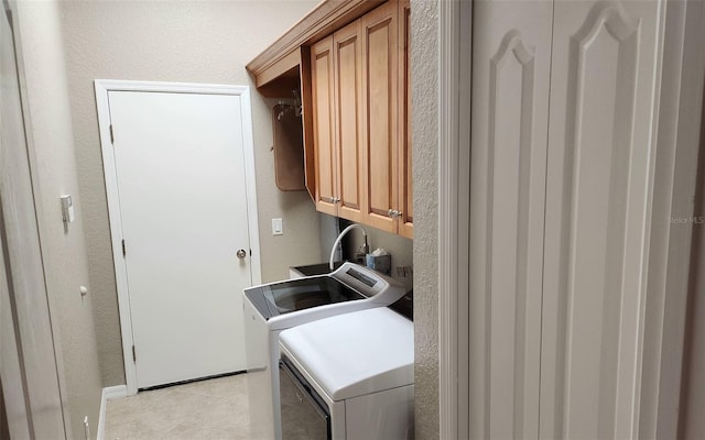 clothes washing area featuring washer and clothes dryer, cabinets, and light tile patterned floors