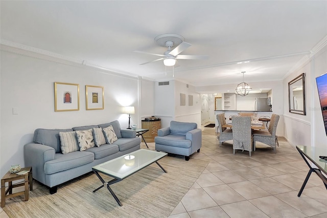 living room with ceiling fan with notable chandelier, ornamental molding, and light tile patterned flooring