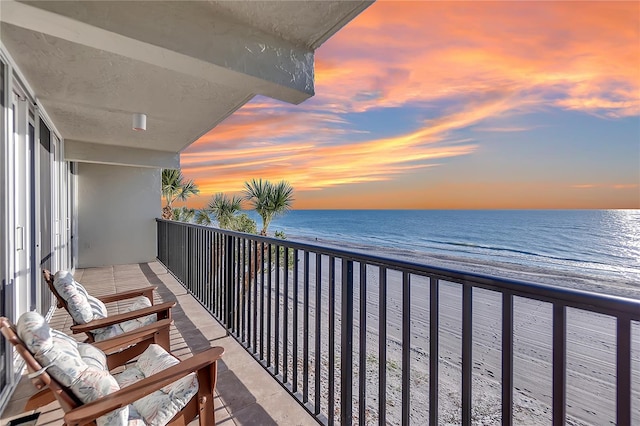 balcony at dusk with a beach view and a water view