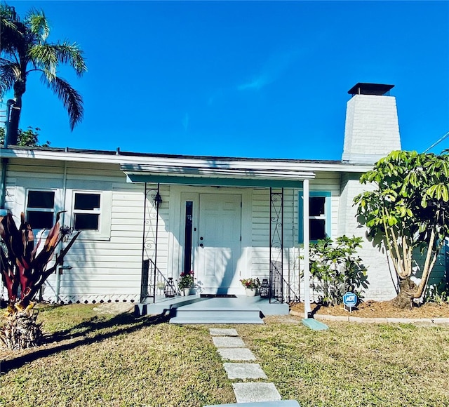 222 27th St W, Bradenton, FL 34205 - view of front of property with a front yard, a chimney, and covered porch