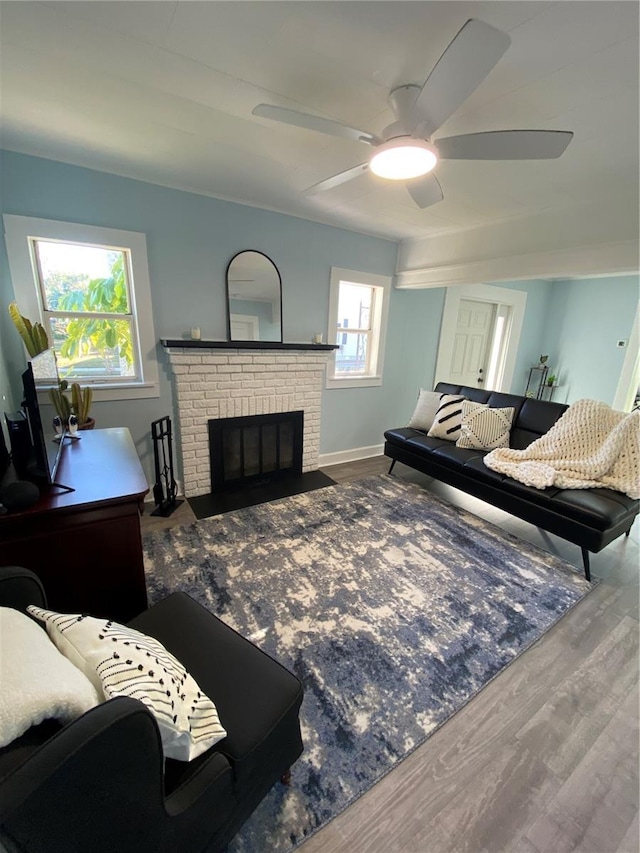 living room featuring hardwood / wood-style flooring, a brick fireplace, ceiling fan, and a healthy amount of sunlight